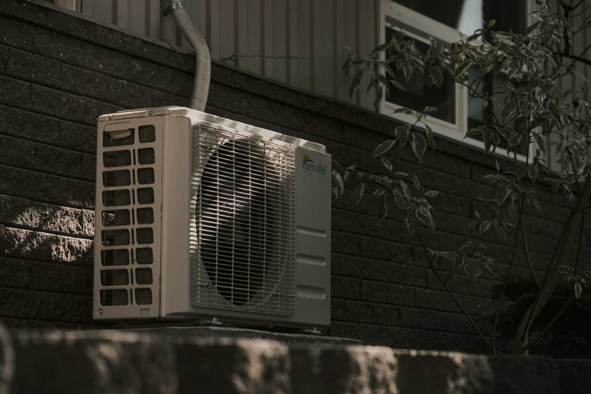 a white air conditioner sitting on top of a brick wall